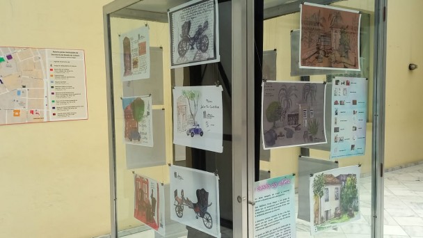 Um cubo de vidro grande com documentos colados por dentro para aprecia&ccedil;&atilde;o - desenhos, fotografias, aquarelas, objetos de arte e de mem&oacute;ria
