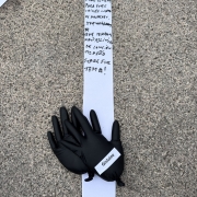 Mãos de escultura colocadas ao chão, com nome "Gislaine", sobre fita de papel com desejos de futuro